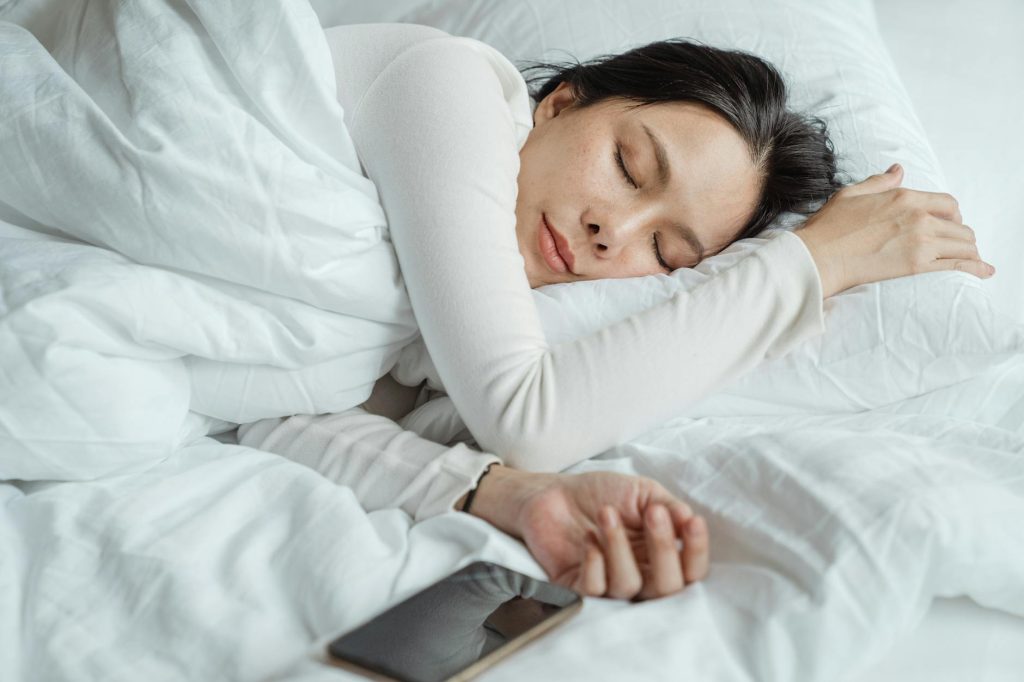 A woman fast asleep with her mobile next to her